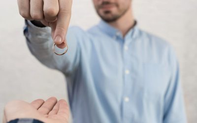 Un homme en chemise bleue remet son alliance à une autre personne, symbolisant les démarches pour un divorce rapide.