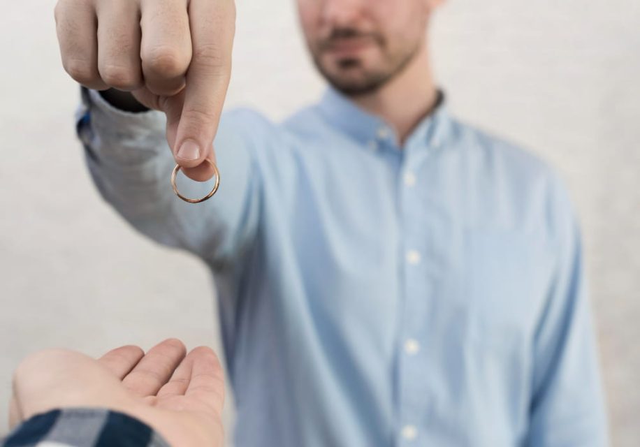 Un homme en chemise bleue remet son alliance à une autre personne, symbolisant les démarches pour un divorce rapide.