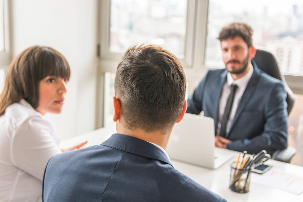 Un couple en entretien avec un avocat ou un conseiller dans un bureau pour un processus de divorce avec médiation.