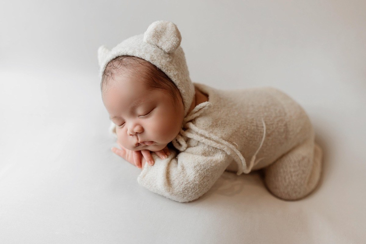 Bébé endormi dans un costume animalier sur fond blanc