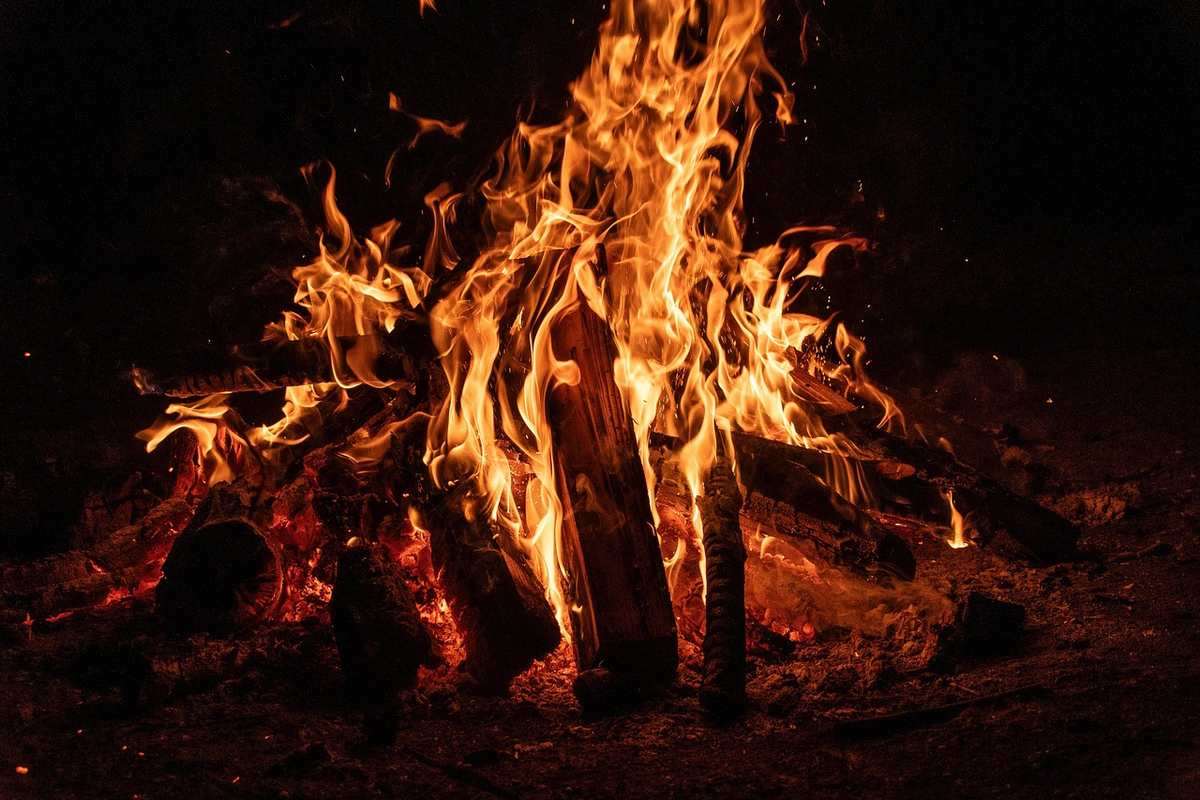 Feu de camp ardent la nuit avec flammes orangées intenses sur bois