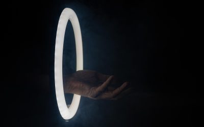 Main droite sortant d'un cercle lumineux contre fond noir