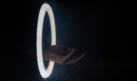 Main droite sortant d'un cercle lumineux contre fond noir