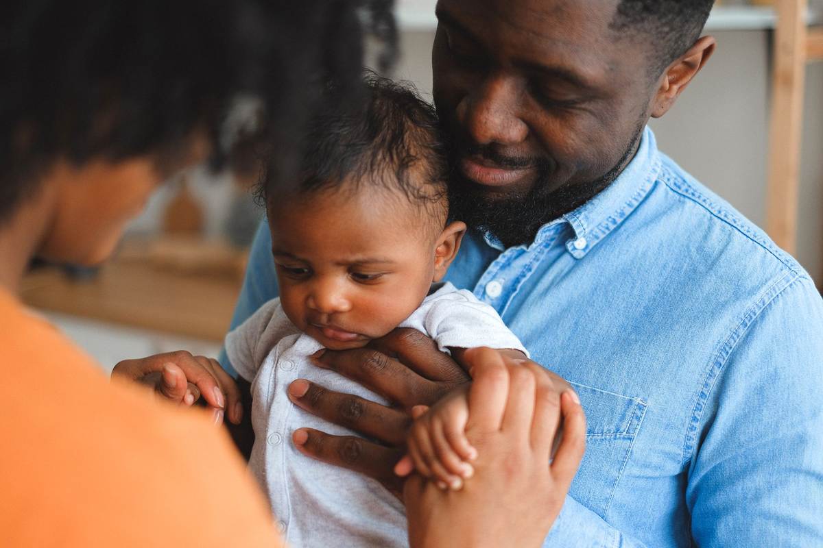 Un père soutient son enfant tandis que la mère le regarde tendrement