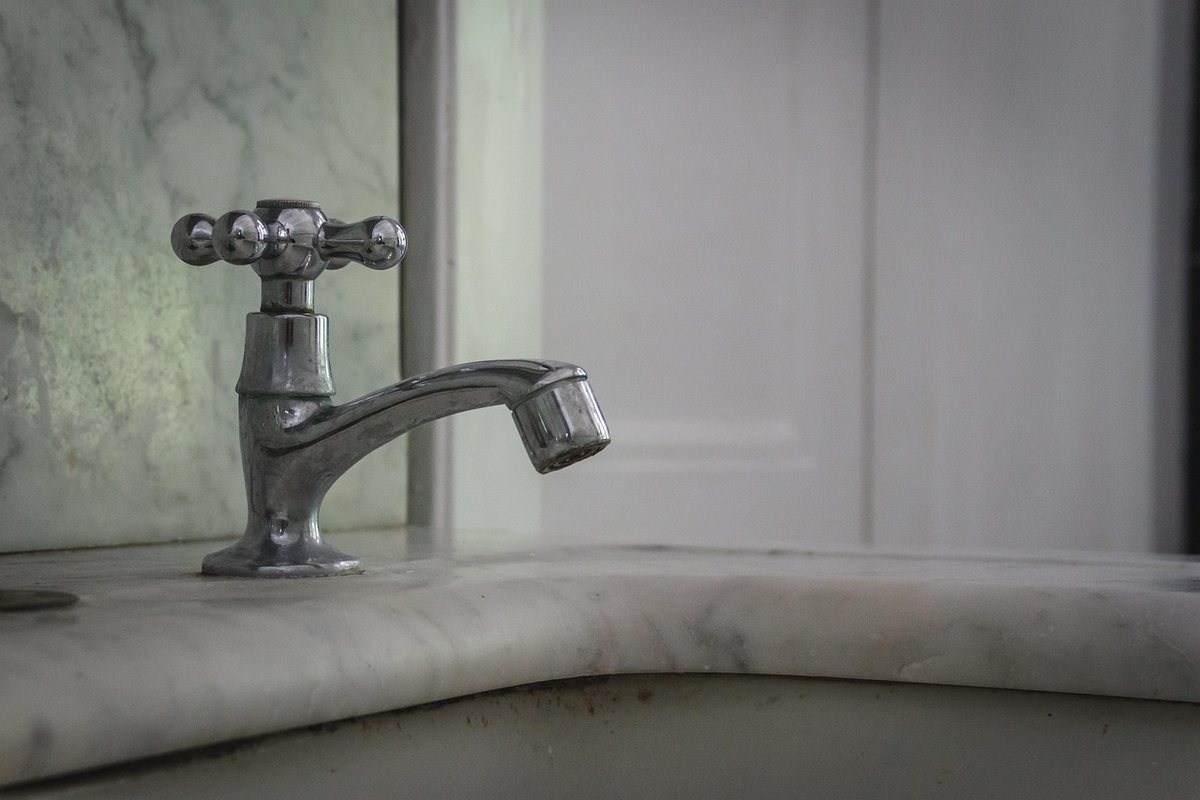 Un robinet à poignée croisée sur un lavabo en marbre