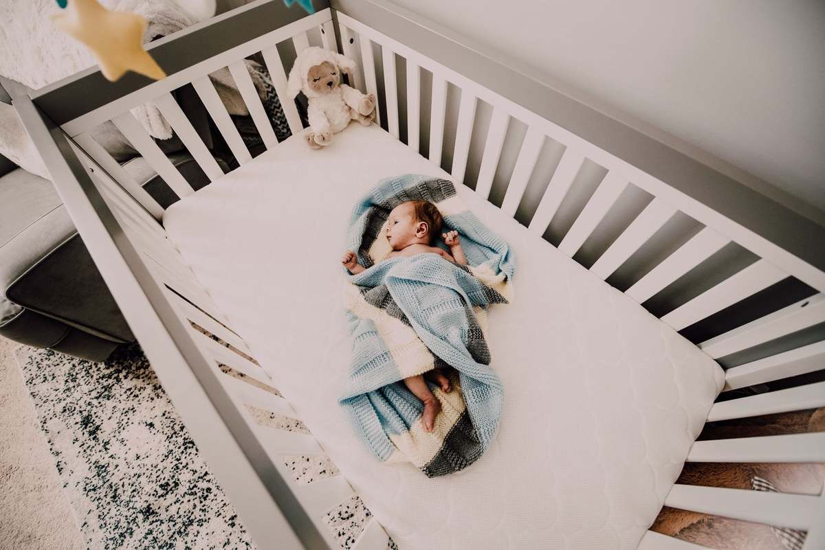 Berceau avec enfant endormi, couvert, et animal en peluche