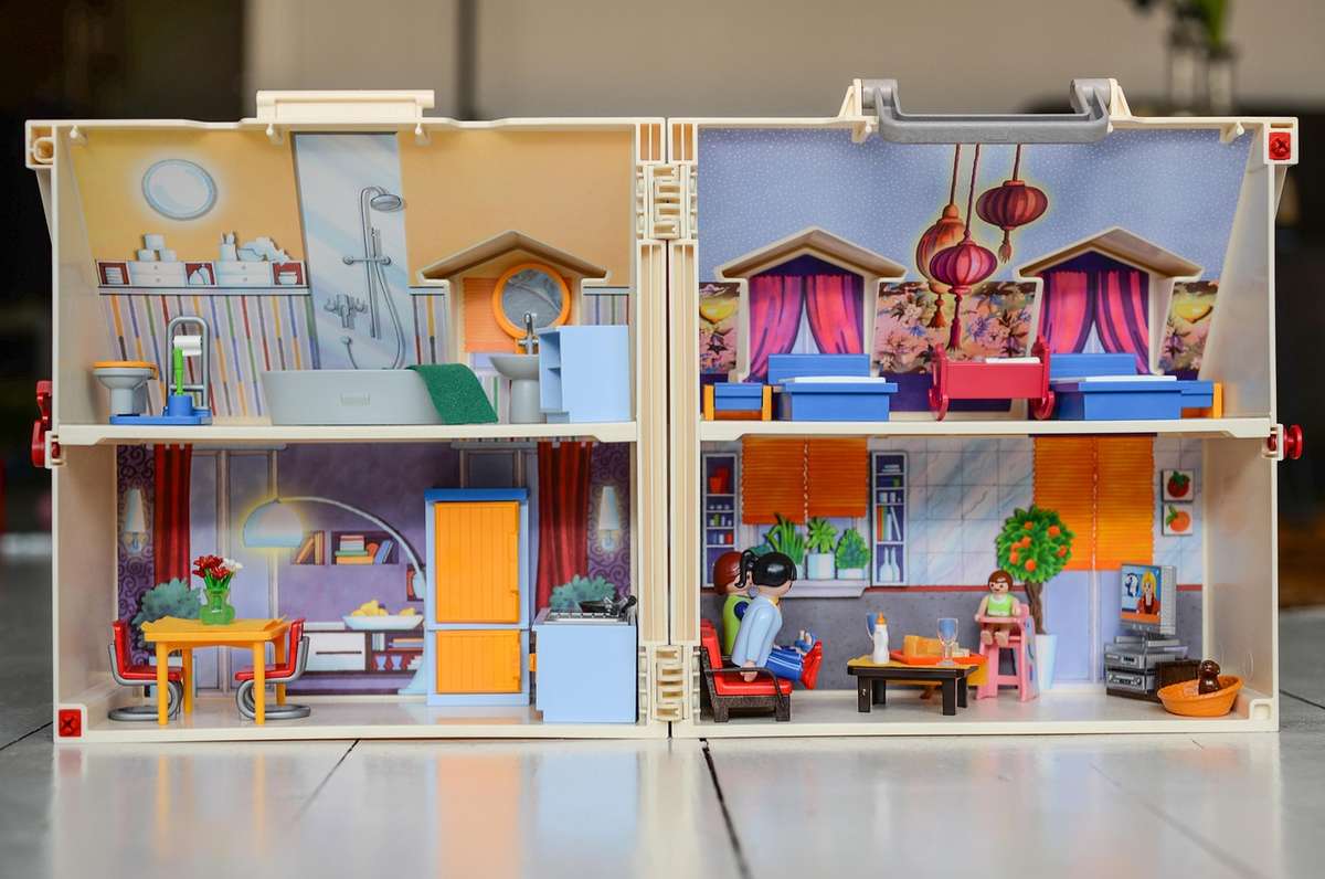 Une maison de poupée à deux niveaux, meublée, avec figurines et accessoires