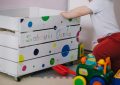 Un enfant manipule une boîte à jouets décorée de points colorés