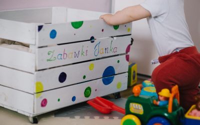 Un enfant manipule une boîte à jouets décorée de points colorés