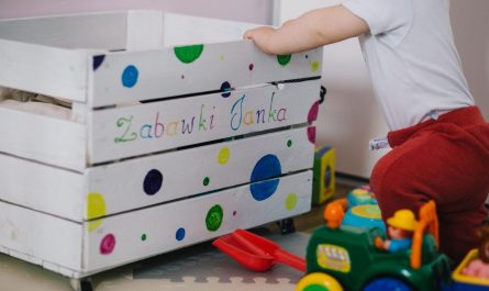 Un enfant manipule une boîte à jouets décorée de points colorés