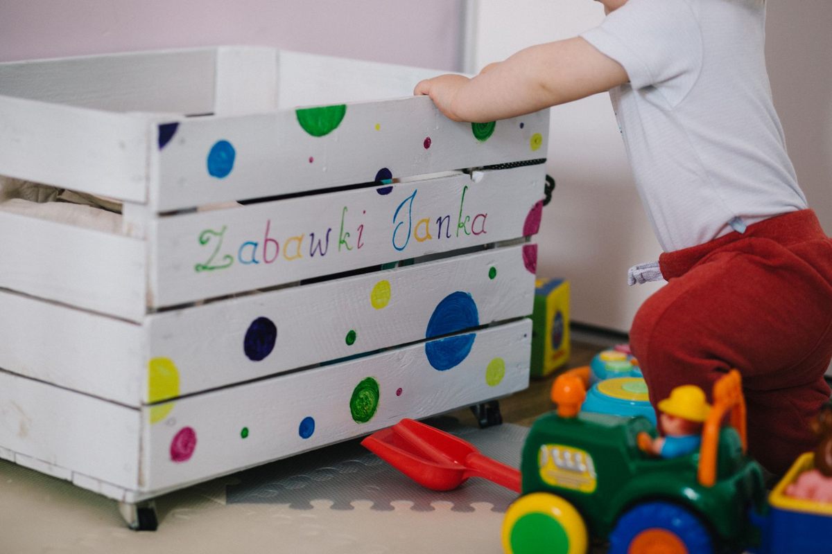 Un enfant manipule une boîte à jouets décorée de points colorés