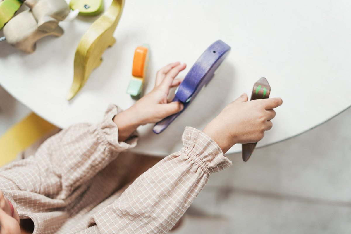 Enfant manipulant des jouets en bois, y compris un xylophone, sur une table blanche