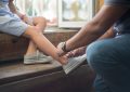 Un enfant assise sur des marches en bois pendant qu'un adulte attache sa chaussure