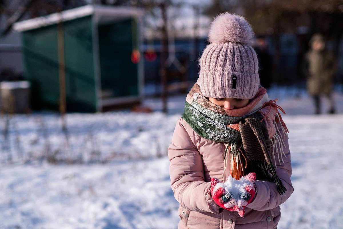 Enfant enfilant un manteau d'hiver Enfant enfilant un manteau d'hiver