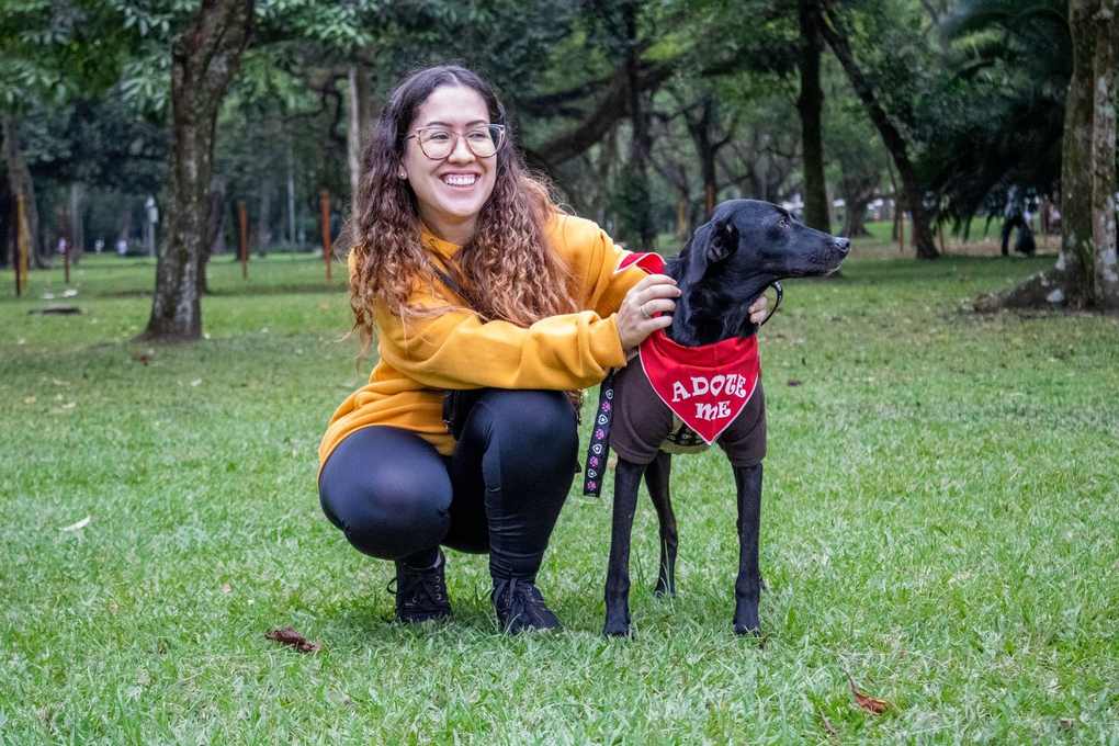 Femme et chien dans un parc, le chien porte un bandana indiquant qu'il a été adopté
