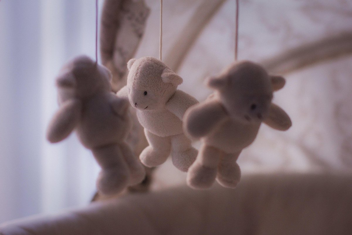 Trois peluches, deux lapins et un ours, suspendues, créant une ambiance douce