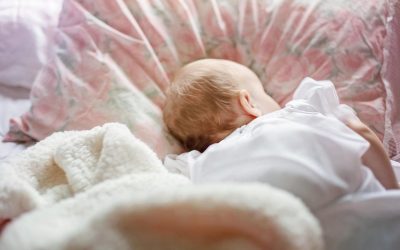 Un bébé dort paisiblement sur un oreiller à motifs roses