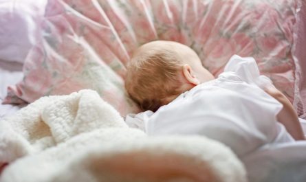 Un bébé dort paisiblement sur un oreiller à motifs roses