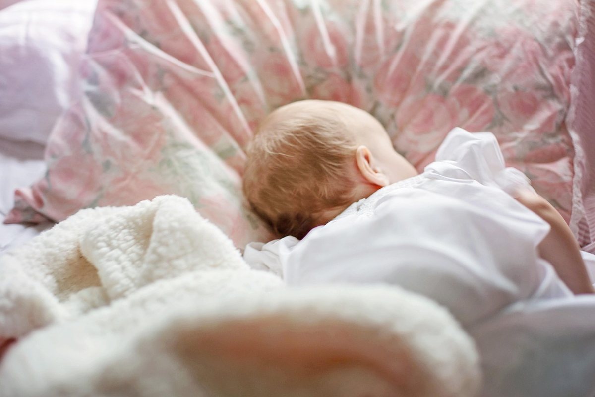 Un bébé dort paisiblement sur un oreiller à motifs roses