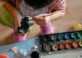 Enfant utilisant un pinceau pour peindre, à une table avec des peintures et des jouets