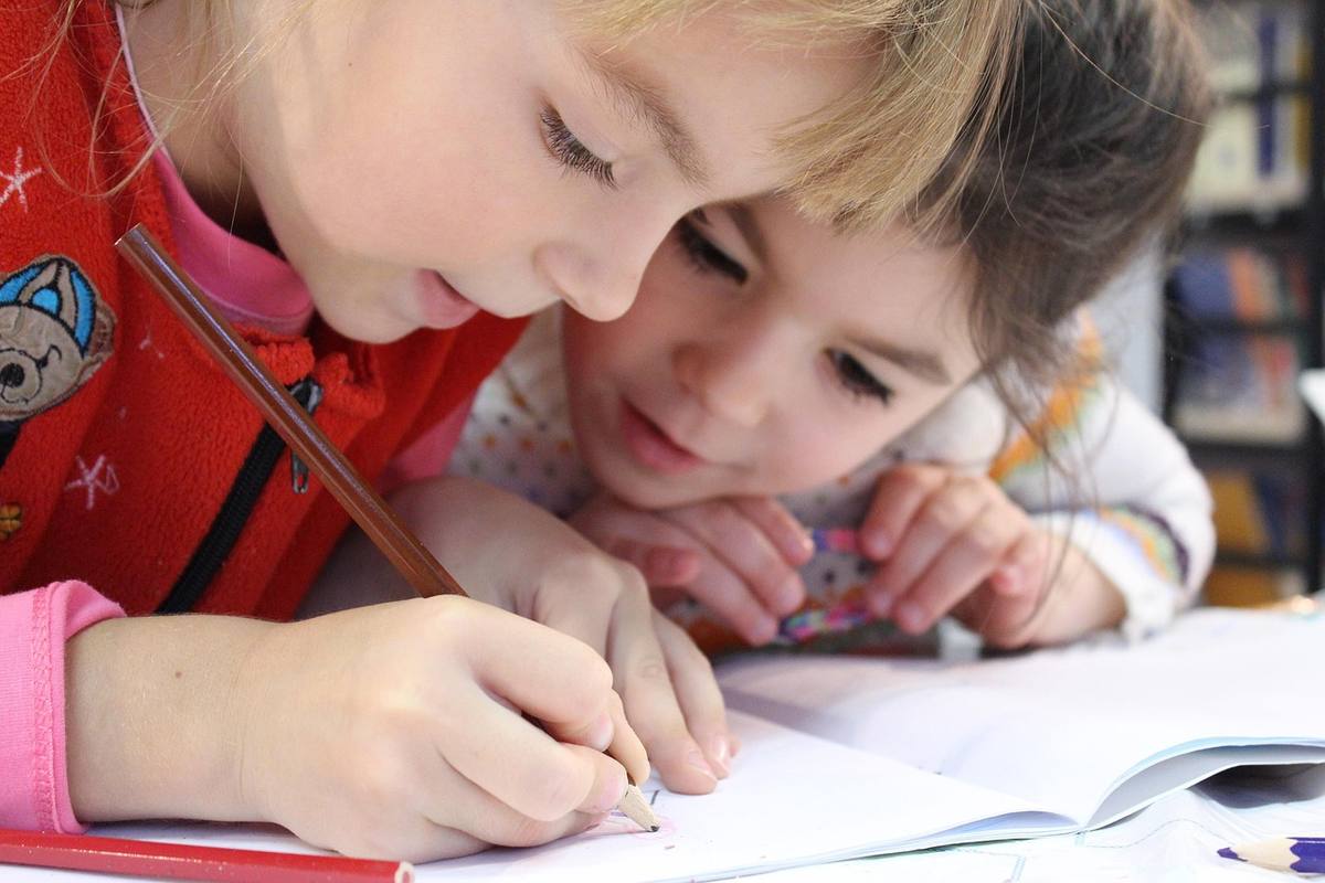 Deux jeunes filles concentrées dessinent ensemble sur une feuille