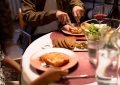 Personnes mangeant et buvant autour d'une table blanche avec assiette, verre et salade