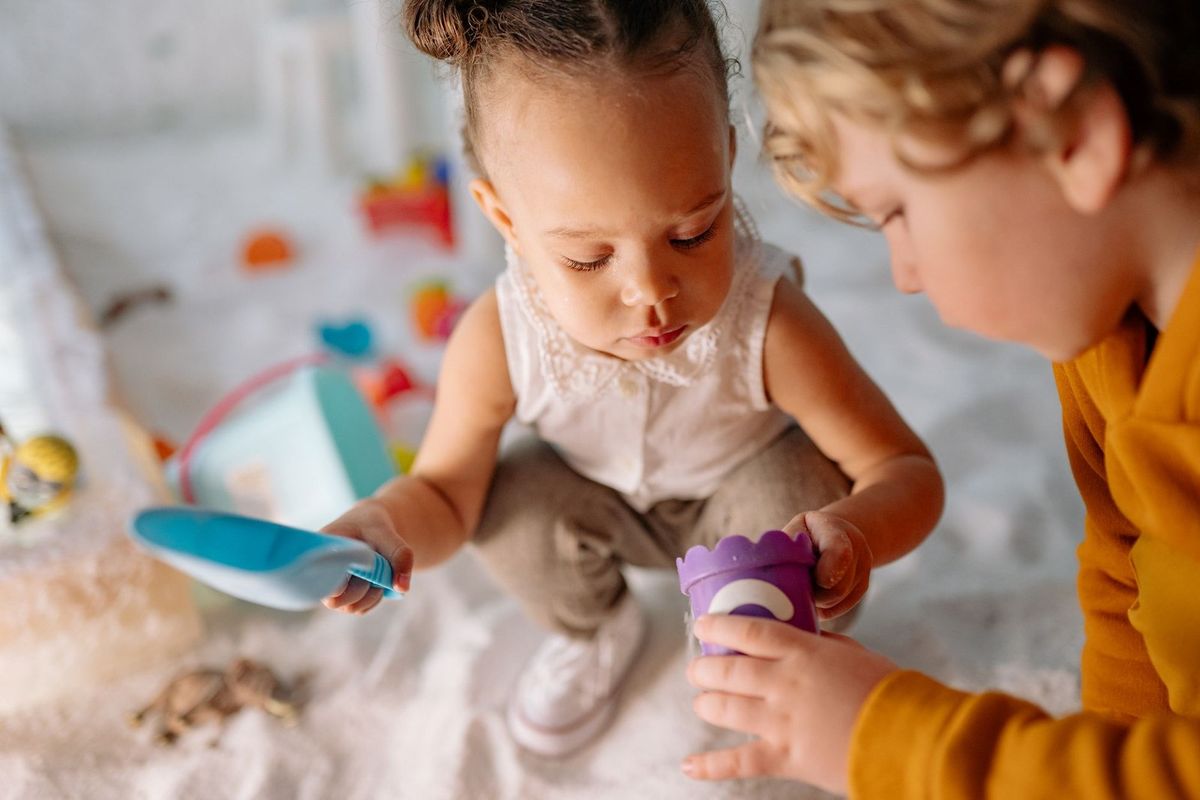 Enfants jouant avec des jouets, assiette bleue et verre violet sur un tapis
