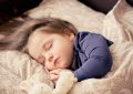 Une enfant dort paisiblement sur des coussins à motifs beiges et bleus