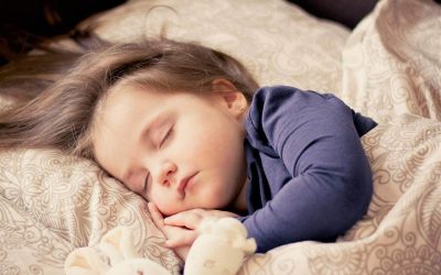 Une enfant dort paisiblement sur des coussins à motifs beiges et bleus