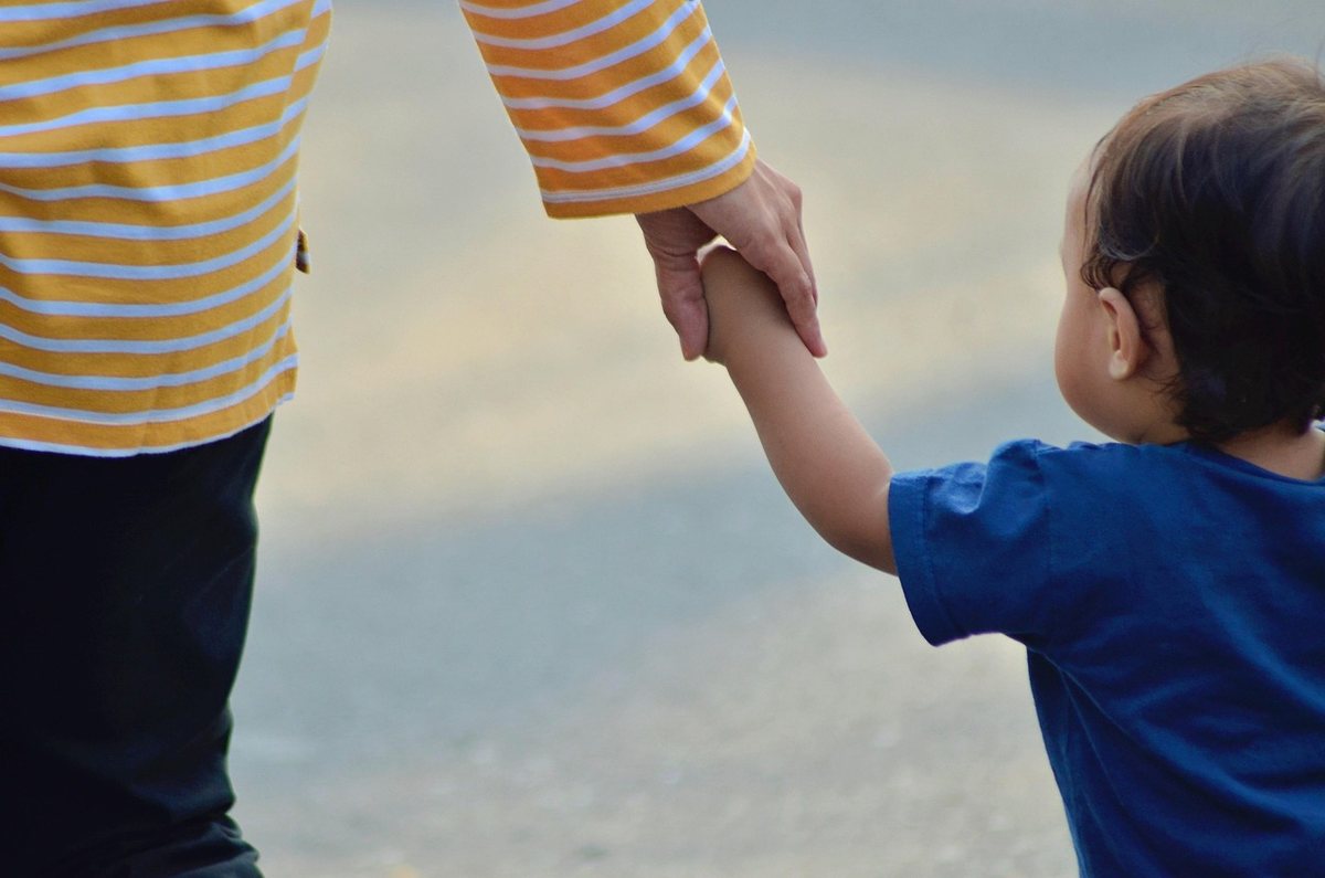 Un adulte tient la main d'un petit garçon marchant ensemble
