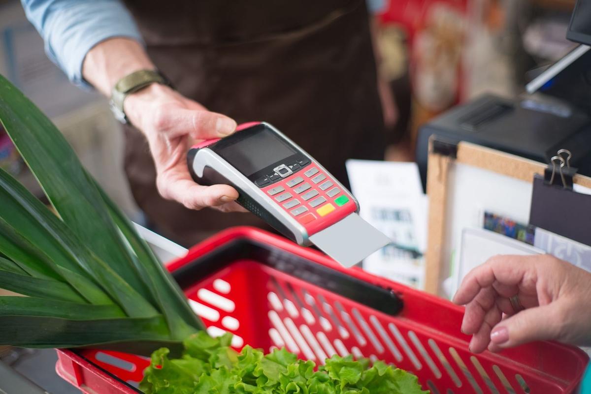 Paiement au terminal de caisse avec panier de courses et légumes