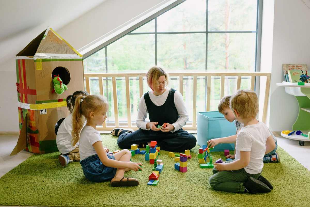 Enfants jouent avec des blocs de construction sous la supervision d'un adulte dans une pièce lumineuse