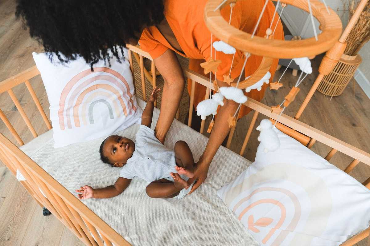 Femme portant un bébé dans un lit décoré de motifs arc-en-ciel